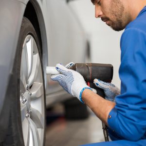 mechanic-with-screwdriver-changing-car-tire-P9CWJFG